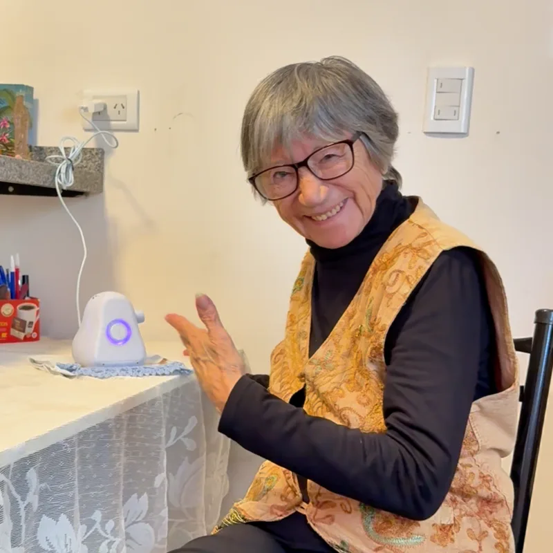 Eva, 78, sonriendo sentada en su casa